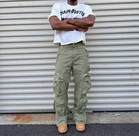 Person wearing a white t-shirt and green cargo pants standing in front of a corrugated metal wall.